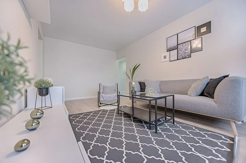 Covered with sheet sofa and floor lamp and packed cardboard boxes in light spacious room of new contemporary house